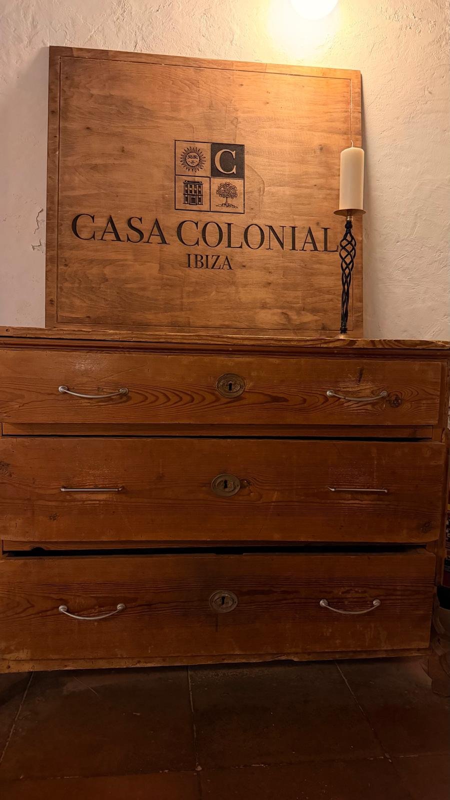 Casa Colonial Ibiza wooden sign above antique pine chest of drawers with candlelight, wedding venue near Santa Eulalia